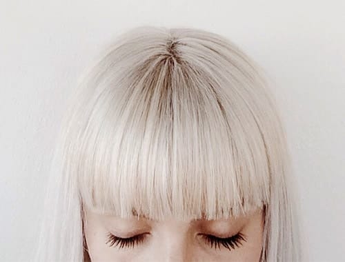 Picture of half a girls head with a bob and big blunt fringes with white blonde hair.