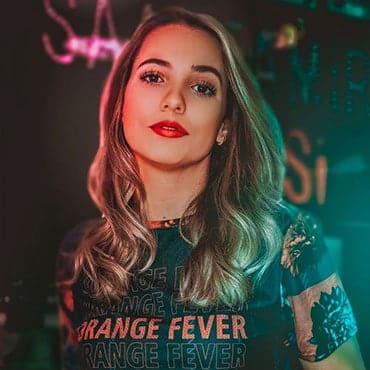 Lady at a night club with wavy long blonde hair wearing t shirt with ORANGE FEVER written many times over it
