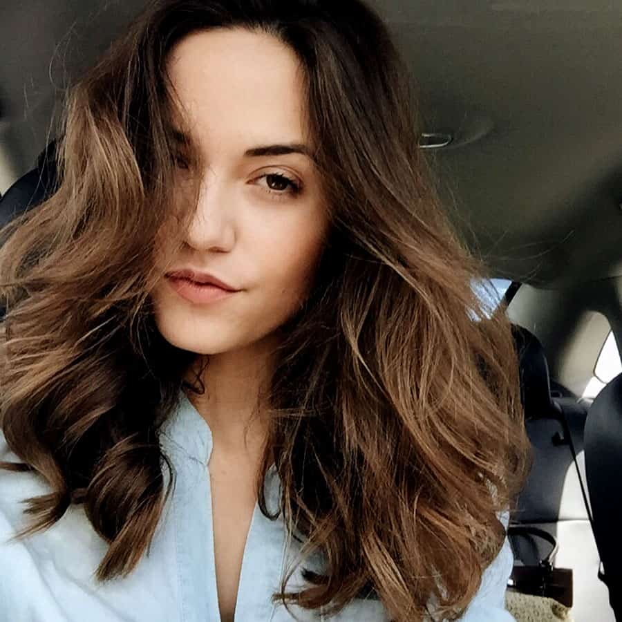 Girl with rich brunette hair that, in a car taking a selfie