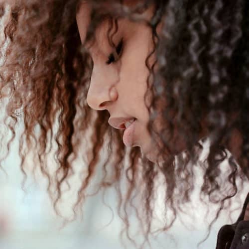 African American girl with very curly hair, leaning forward with eyes closed