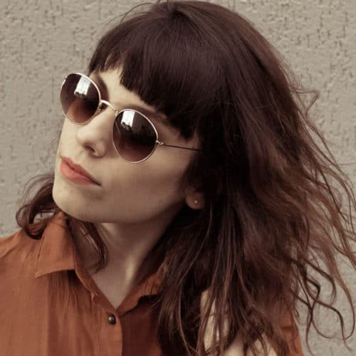 Rich warm brunette wearing dark sunglasses and warm brown blouse