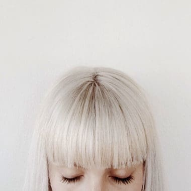 Picture of half a girls head with a bob and big blunt fringes with white blonde hair.