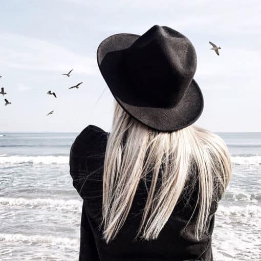 Meisje met zwarte fedora hoed met wit blond haar