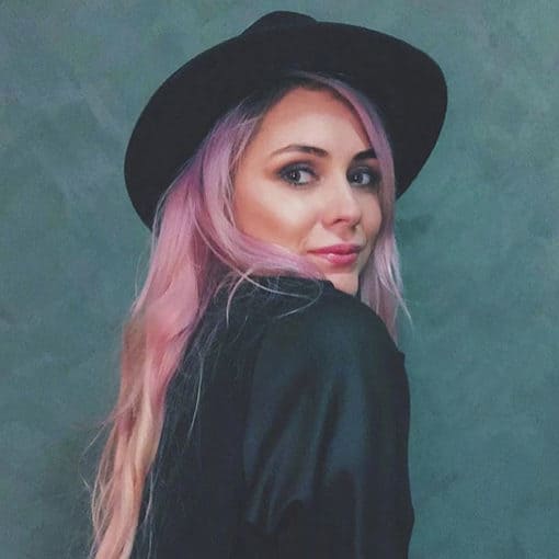 Very long vibrant pink hair on a lady wearing a black brimmed hat and a black jacket