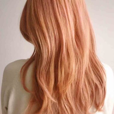 Back of female head with long peach coloured hair, wearing white jumper