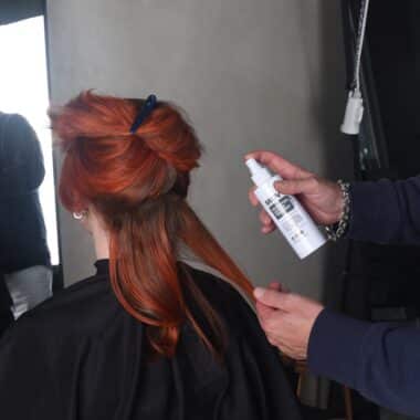 Revolution Spray being applied to curled, red hair during styling.