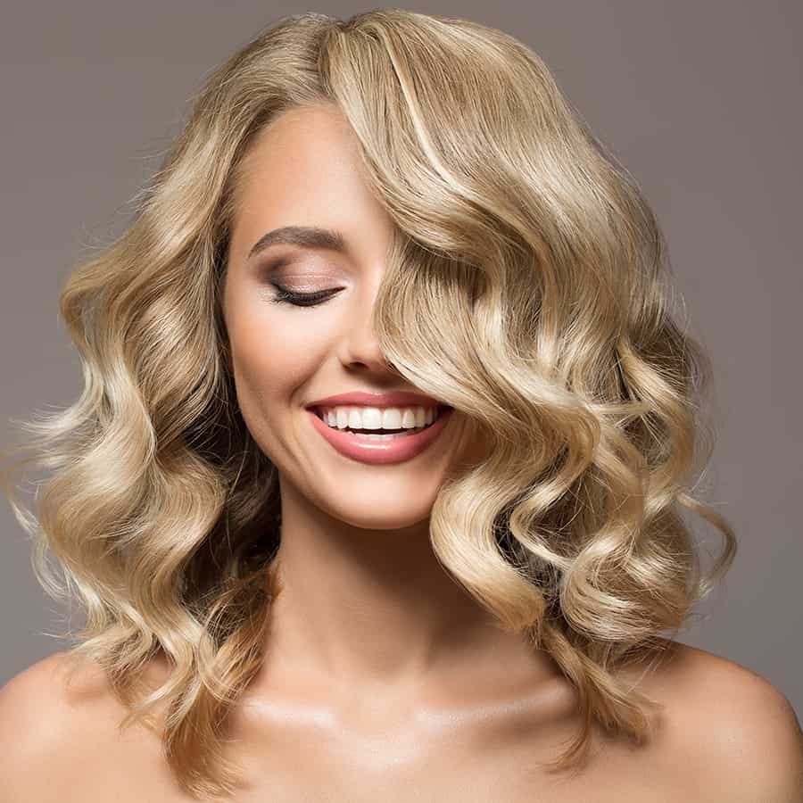 Blonde model with curly hair draping over half her face