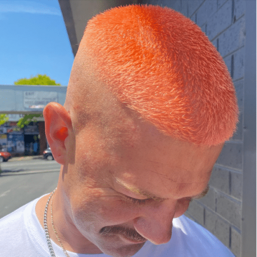 Man with a buzz cut, coloured to a bright peach colour