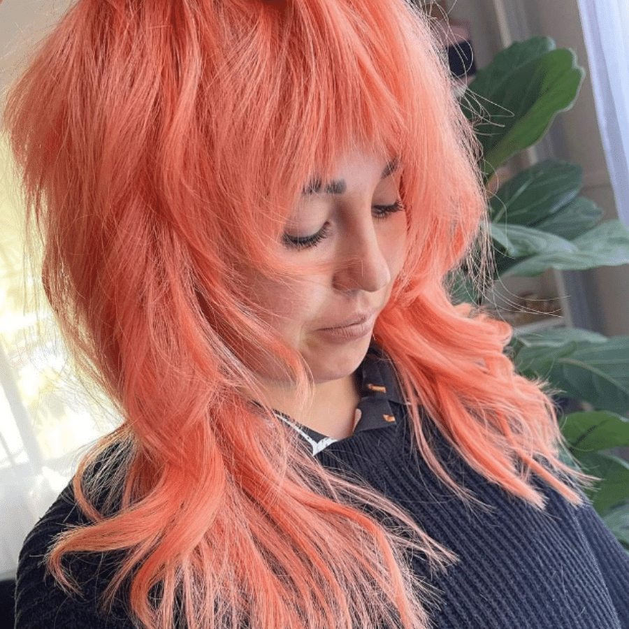 Girl with bright peachy hair cut into a shaggy 70's hairstyle
